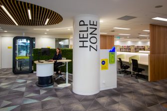 A pod and large column with a single silent study booth and individual study desks in the background. 'Help Zone' is in large print on the column.