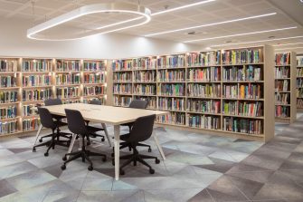 A group study desk enclosed by shelves of books on three walls. More rows of shelves are in the background.