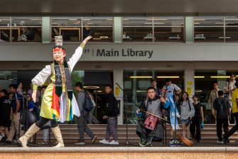 Outside Main Library during Languages Festival. A woman in traditional dress is performing a Mongolian bowl dance, a musician is seated behind, playing the horsehead fiddle.