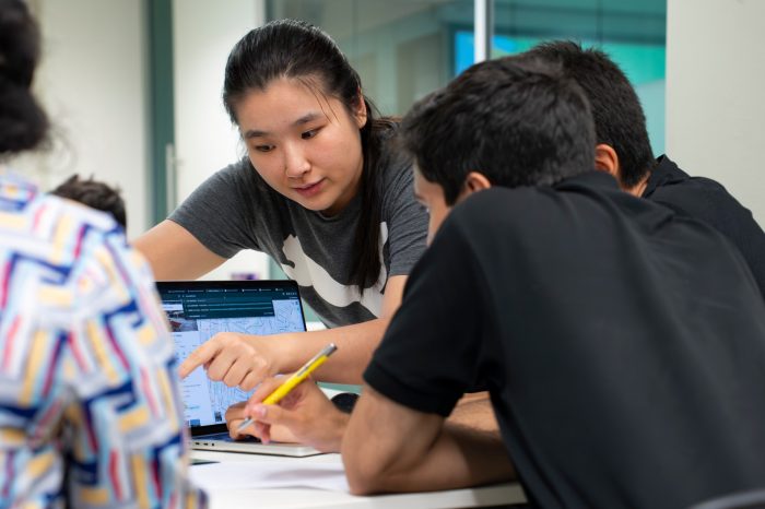  Students and Library Peer Mentors in discussion and looking at a laptop screen.