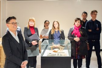 A photo with several people standing around a display case, looking towards the camera and smiling. 