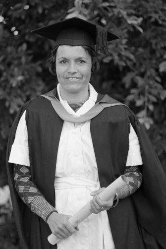 Pat O’Shane portrait picture wearing graduation gown and hat, holding rolled up graduation certificate