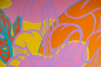 A multicoloured abstract mural comprised of pink, yellow, purple, orange, and green pigments