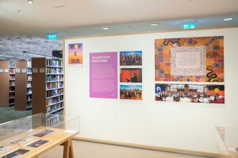 Exhibition main wall with image of the Uluru Statement and photos of delegates and speakers at the Regional Dialogues and First Nations Constitutional Convention.