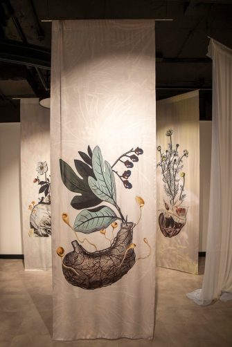 Suspended fabric panels feature anatomical forms and botanic imagery.