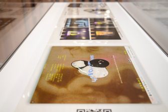 Side view of a glass display unit containing three transparent sheets printed with text and abstract images 