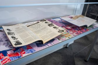 A glass display cabinet containing two open magazines propped up against a colourful backdrop