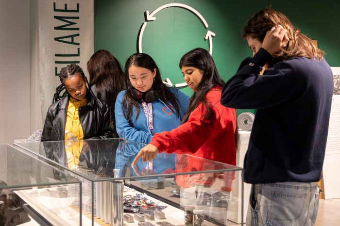 Four university students examine items in a museum display case. 