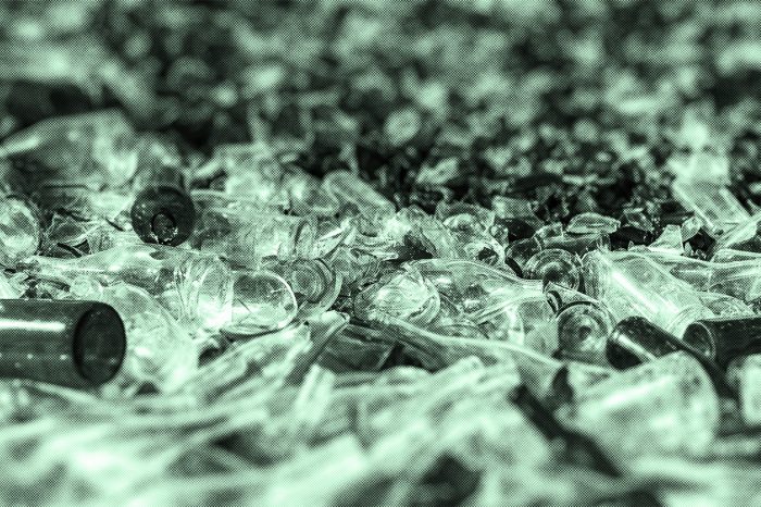 Numerous pieces of broken glass of varying sizes and shapes, seen at close range in shades of green.