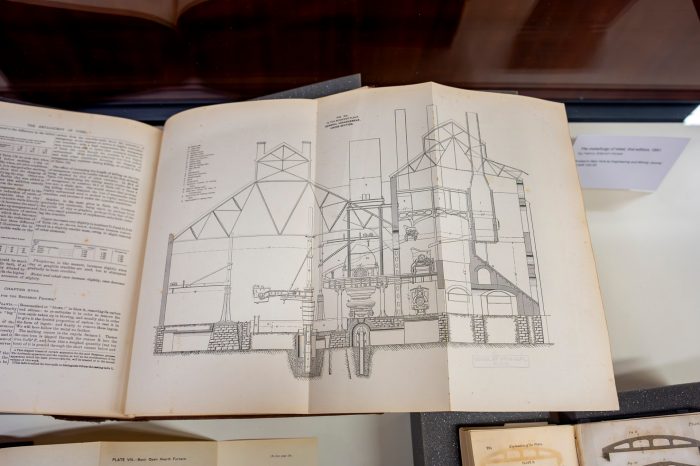 A book opened up to a fold-out page showing a detailed black and white schematic of a furnace structure