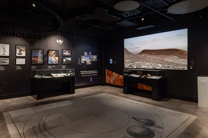Exhibition room featuring a solar system floor map and a large landscape projection.