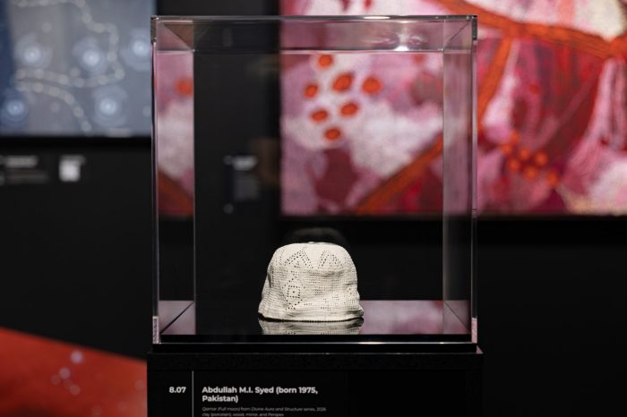 A black pedestal showcasing a clear case with a white, patterned porcelain cap that looks like a moon, an artwork by Abdullah M.I. Syed.