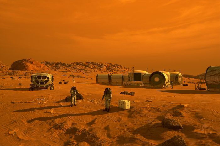 An illustration captures two astronauts in white suits standing on a rocky, rust-colored Martian plain beside a modular multi-story habitat under a hazy, orange sky.