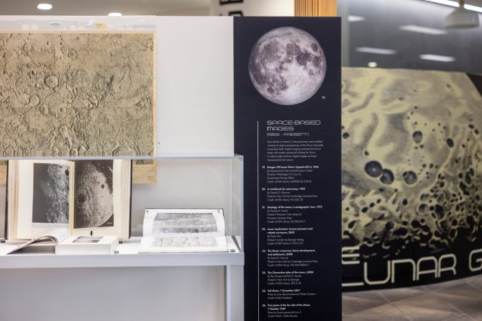 A detailed exhibition panel titled "Space-Based Images" featuring historical lunar photographs, informational text captions, and a textured moon surface model on display.