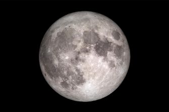 A giant, glowing grey sphere against a black void. Its surface is a rugged landscape of circular, bowl-shaped pits and jagged ridges that cast long, dark shadows.