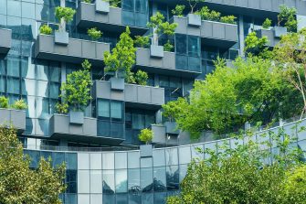 A dark grey modern apartment building with a vertical garden and trees. 