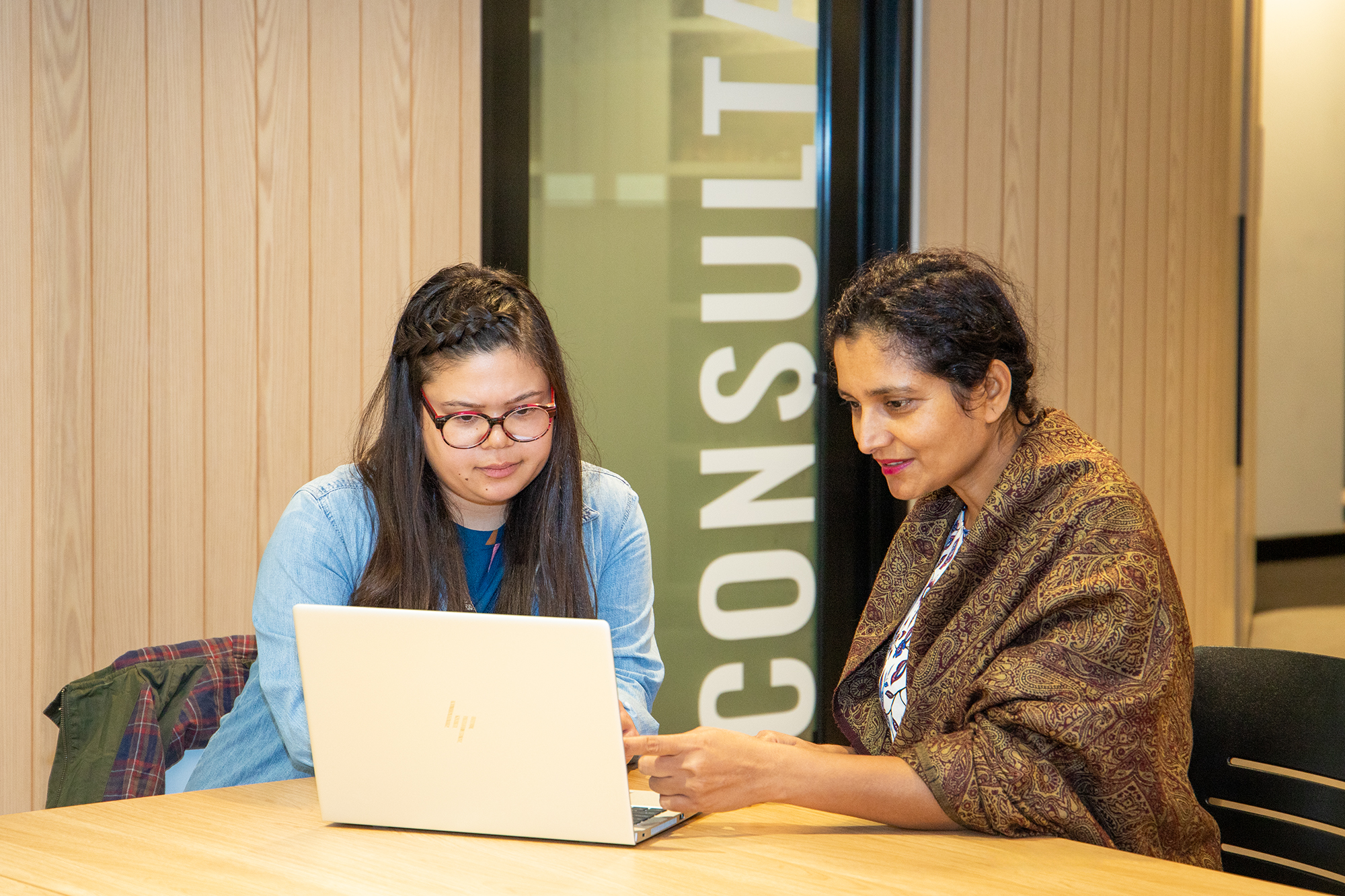 A library staff member and a student sitting in front of a laptop in a consultation room