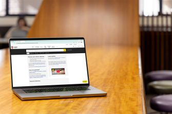A laptop on a Library bench desk with its screen opened to Library collection website.