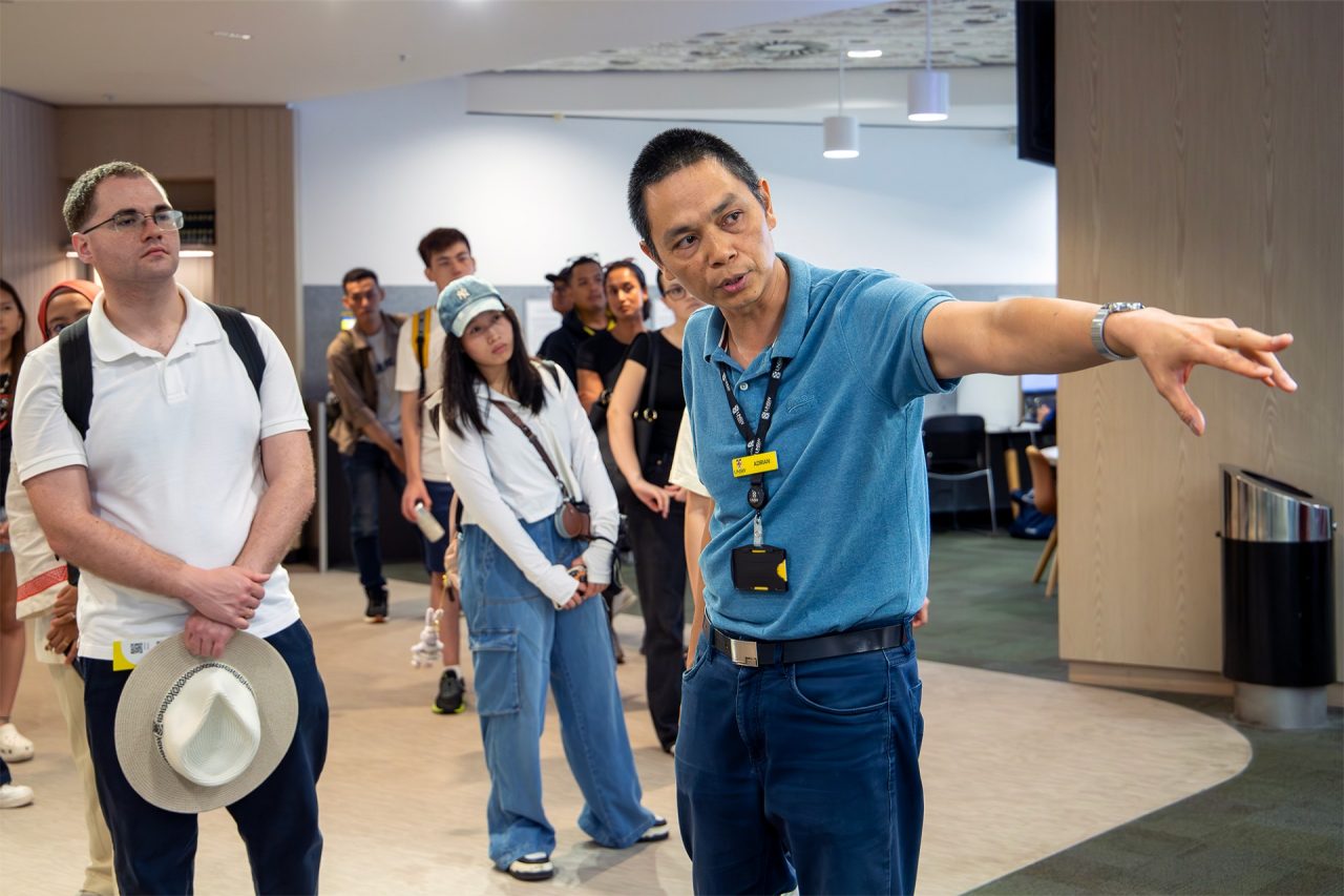 Library staff member leading a tour at the Law Library, pointing ahead while participants follow his gesture to look at something off camera.