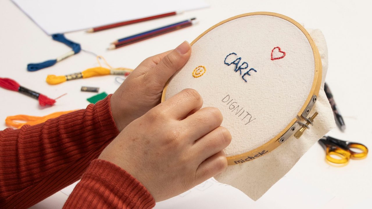 An assortment of fabric squares featuring words and drawings stitched in coloured thread.