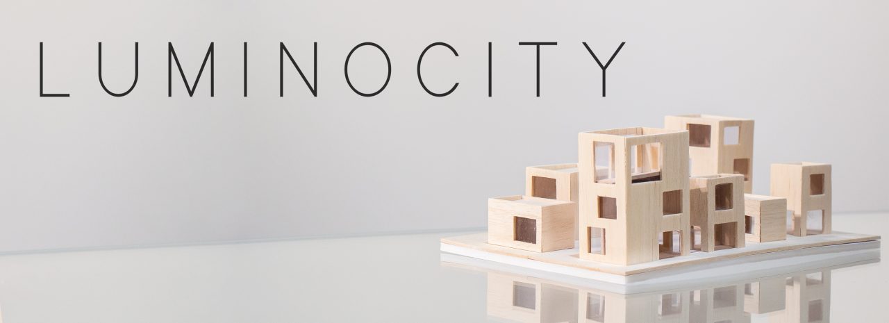 A photo of a beige three-dimensional architectural model on top of a reflective white table surface. At the top of the image is the text "Luminocity".