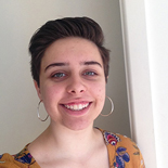 A photo of a young woman with short brown hair and hoop earrings looking at the camera