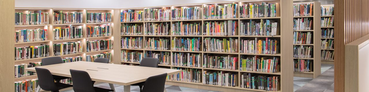 Print collection displayed in book shelves with collaborative desk in front
